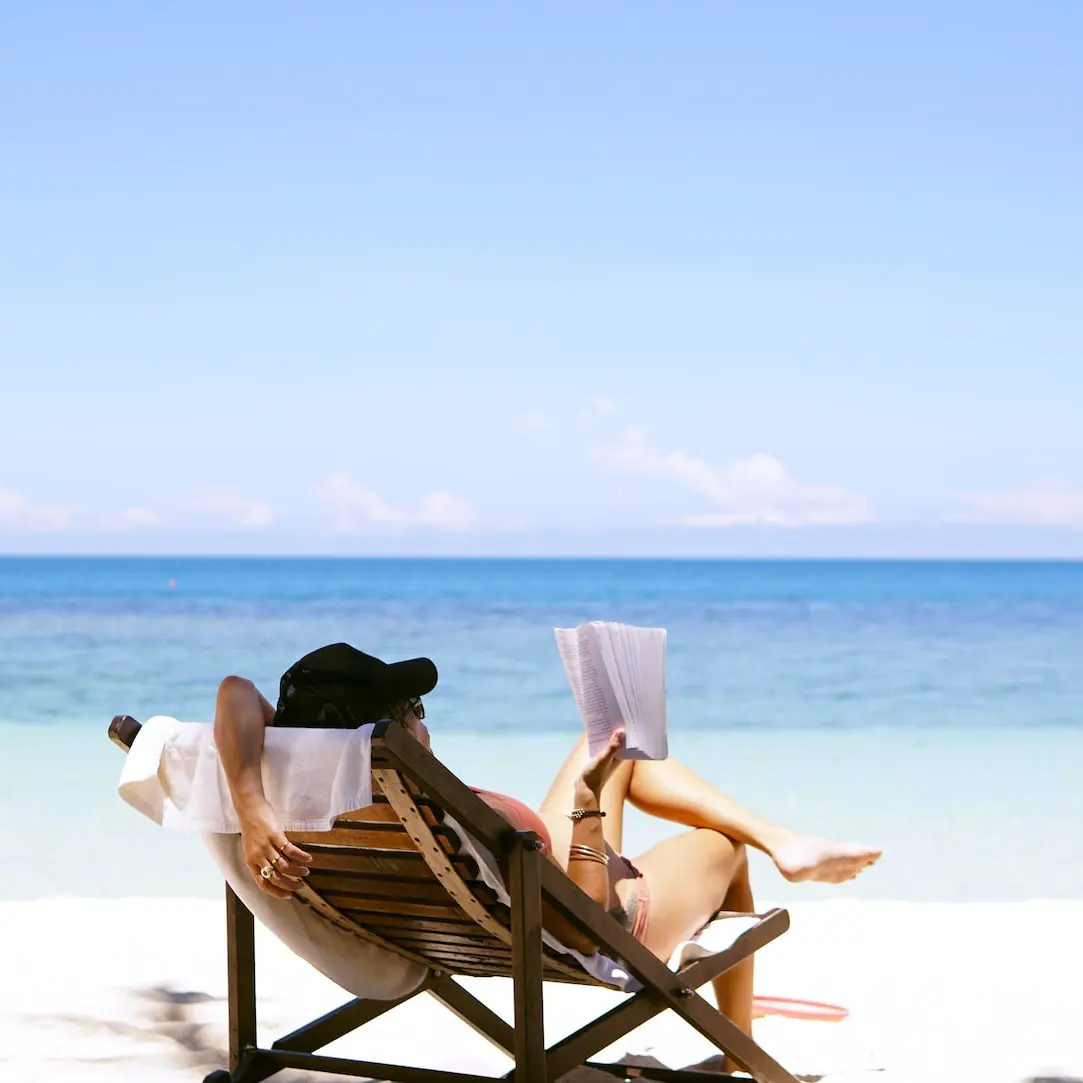 woman sits on brown wooden beach chair